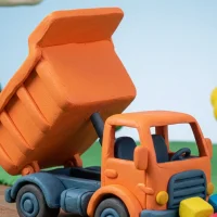 粘土細工で作られたオレンジ色のダンプトラックとカラフルな積み荷(クレイアニメ風)